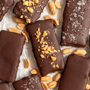Several vegan butterfingers on a sheet of parchment paper, with peanuts.