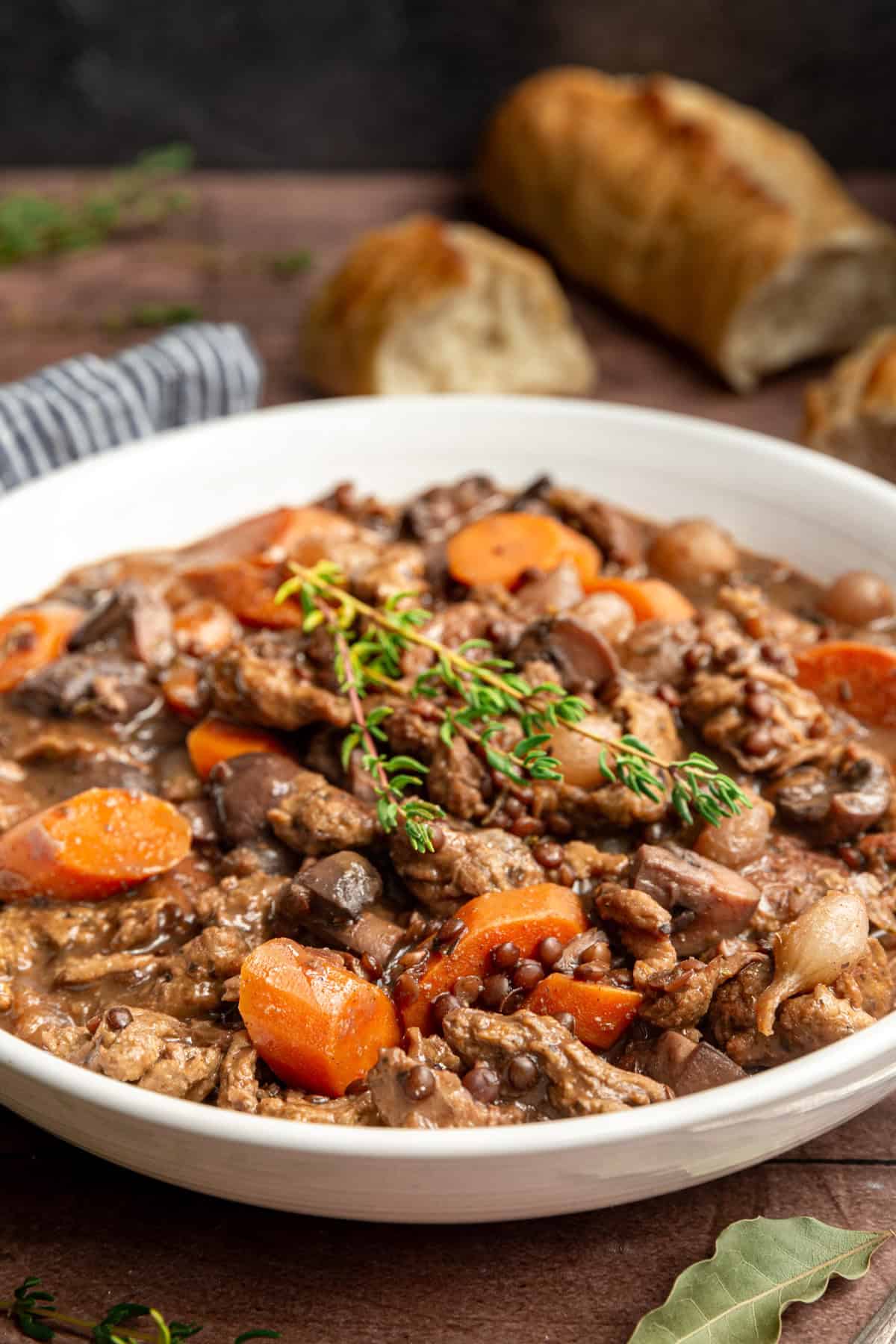 A bowl of vegan coq au vin with a garnish of thyme, ready to serve.