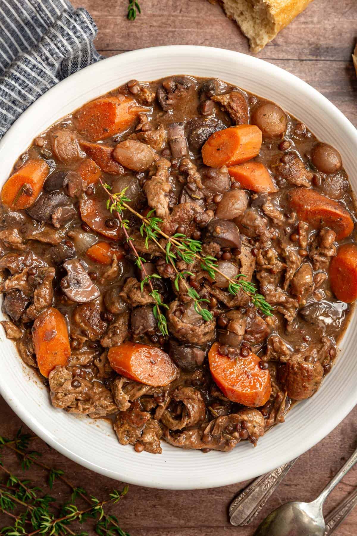 A bowl of vegan coq au vin with a garnish of thyme.