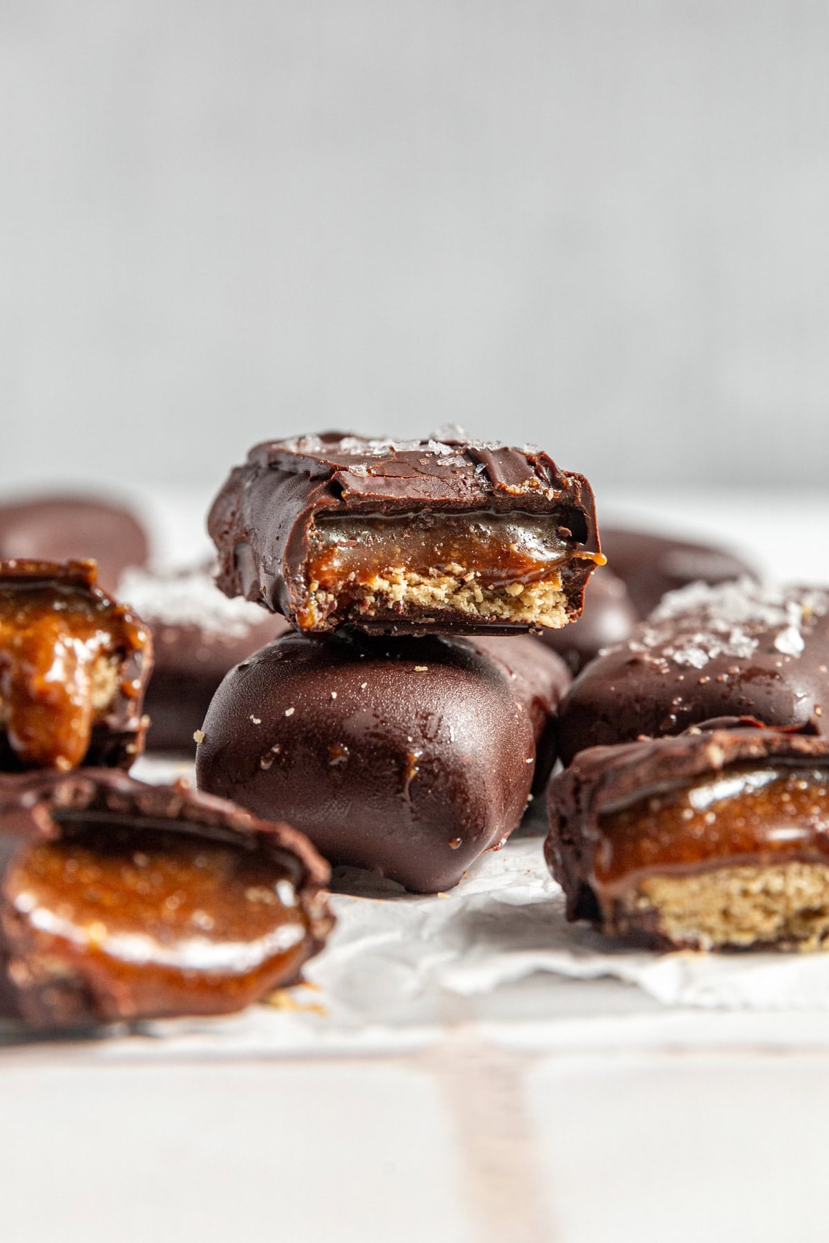 Several vegan twix bars that have been bitten into, revealing the caramel and cookie layers.