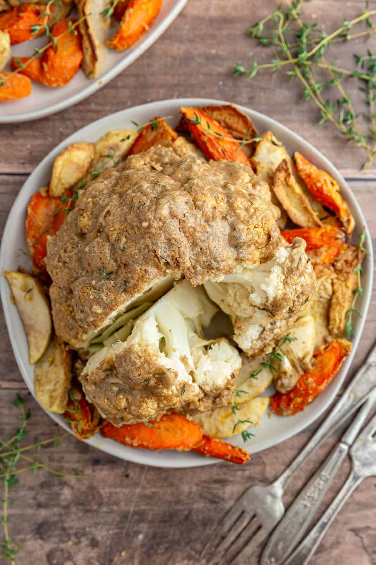 A plate with a Whole Roasted Cauliflower with a wedge cut out.