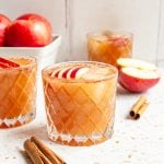 An apple mocktail sitting on a countertop with a box of apples.