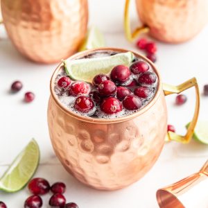 A mule glass with a cranberry mocktail, garnished with frozen cranberries.