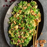 A platter of Vegan Brussels Sprouts Salad, with serving utensils, ready to serve.