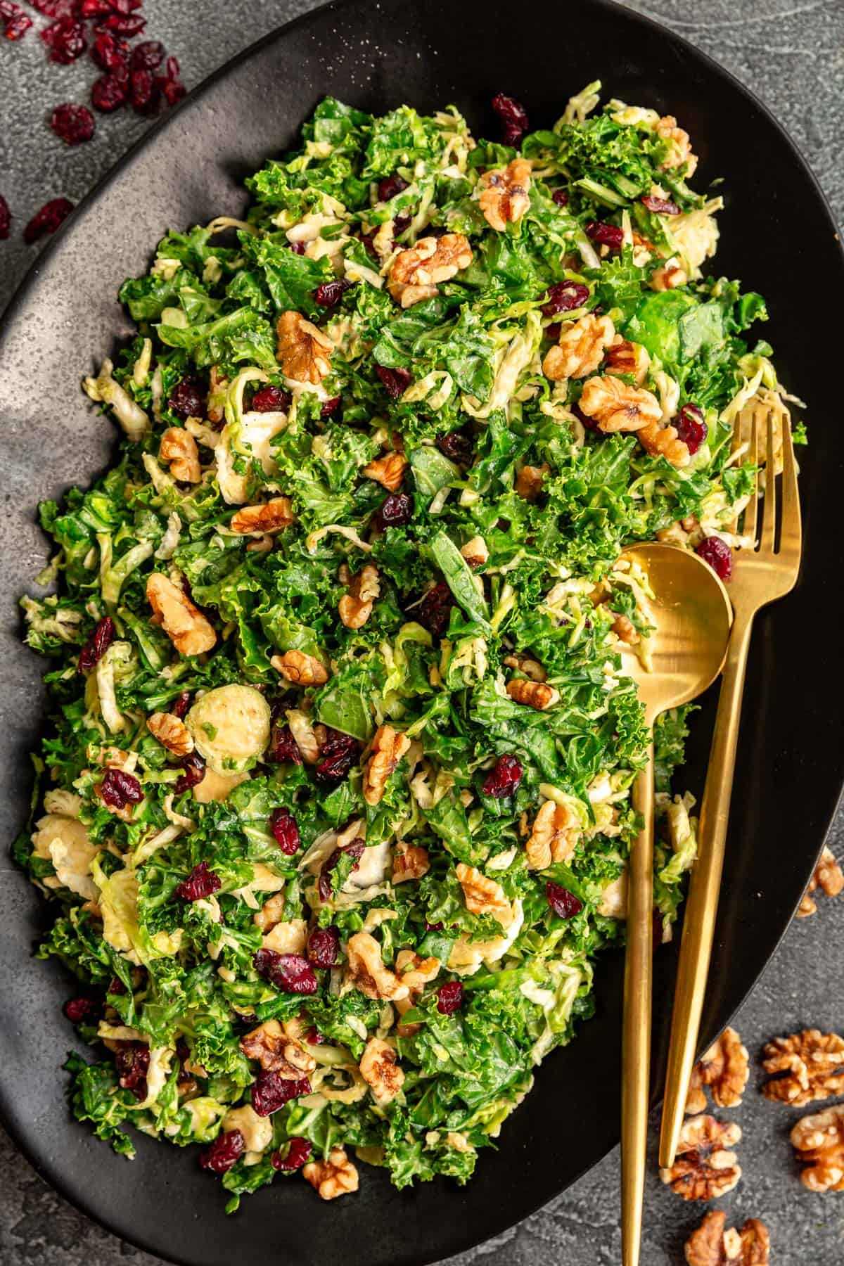 A platter of Vegan Brussels Sprouts Salad, with serving utensils, ready to serve.