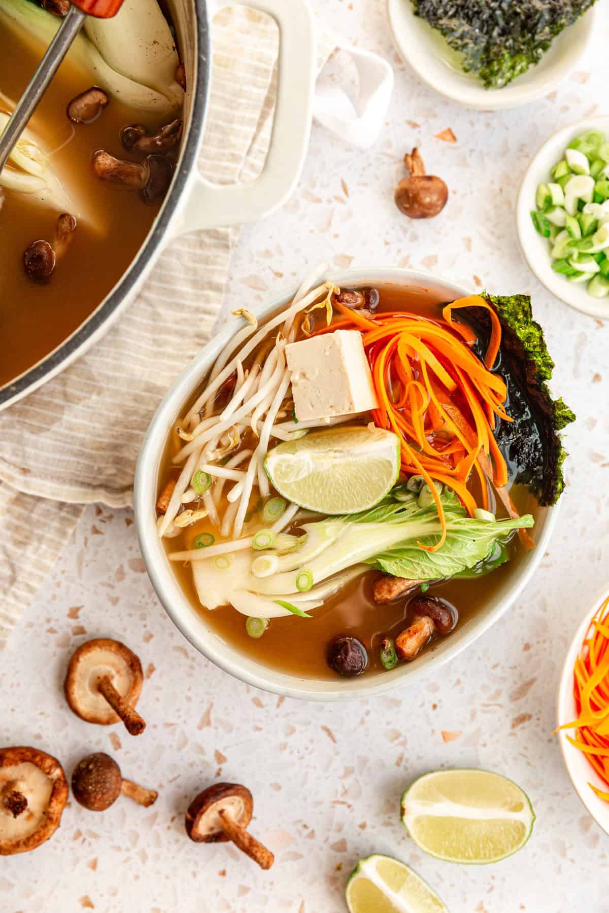 A pot of freshly cooked miso soup with bok choy and a bowl of soup with garnishes.