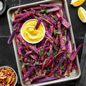 A tray of purple sweet potato fries with a dish of aioli.