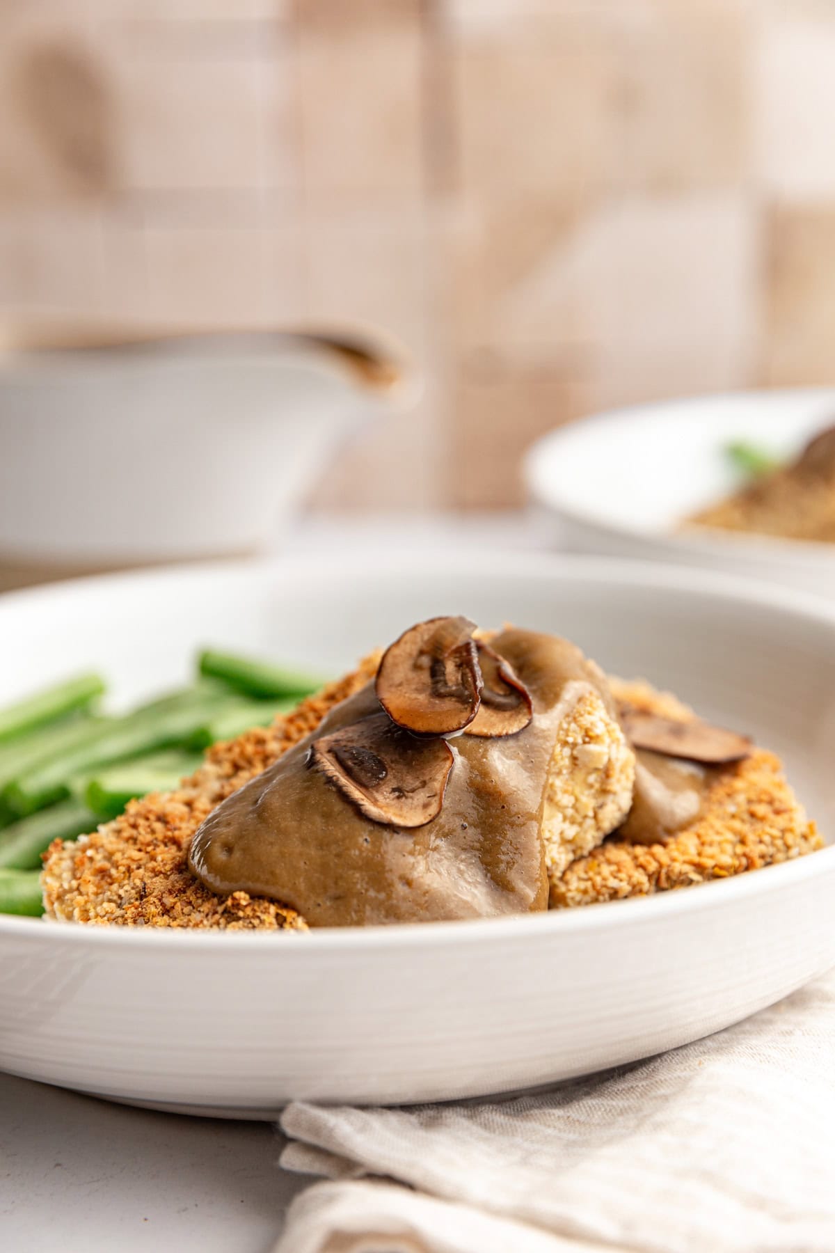 Two slabs of tofu with mushroom gravy drizzled on top, with extra mushrooms on the gravy.
