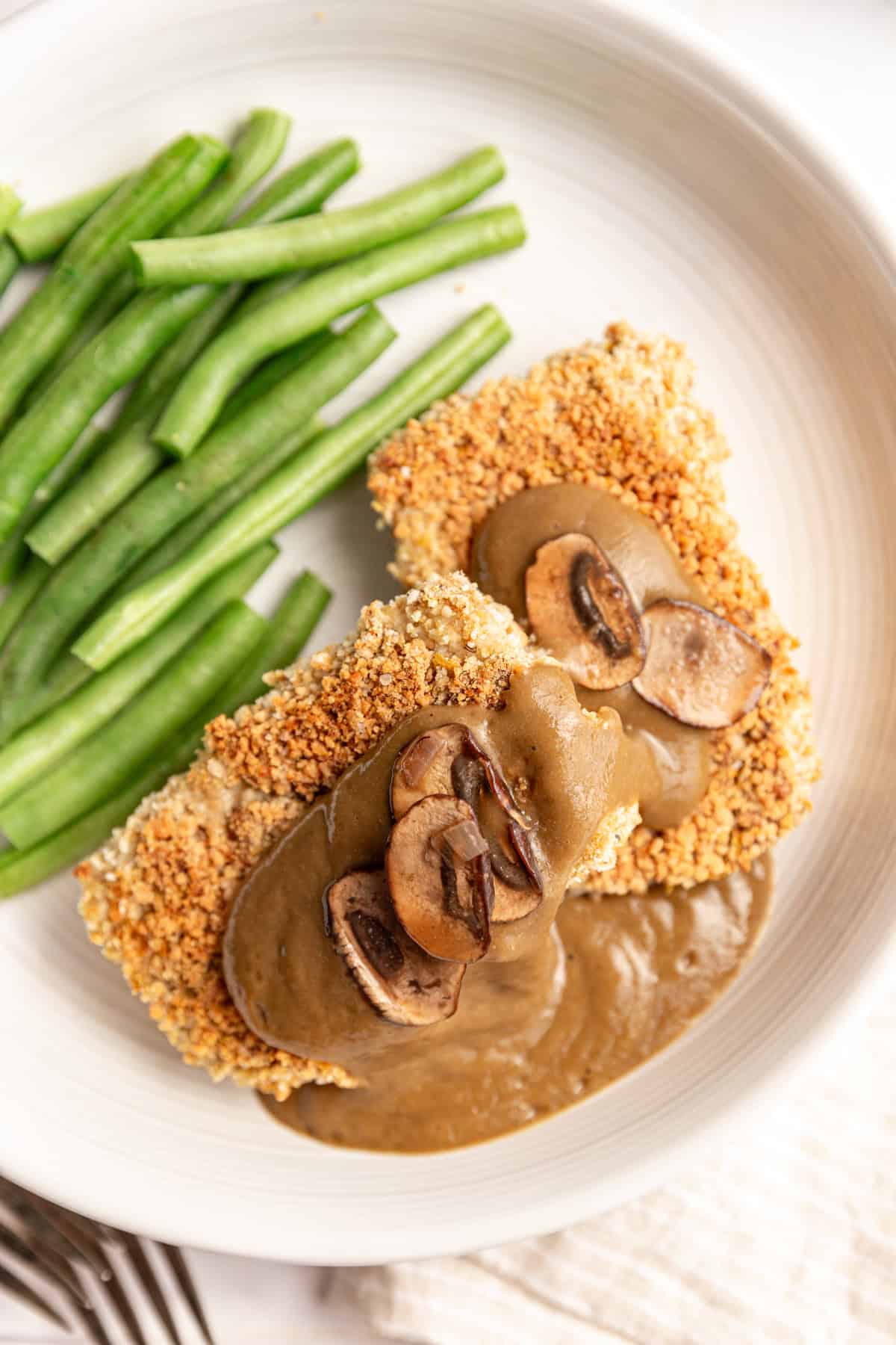 Two slabs of tofu with mushroom gravy drizzled on top, with extra mushrooms