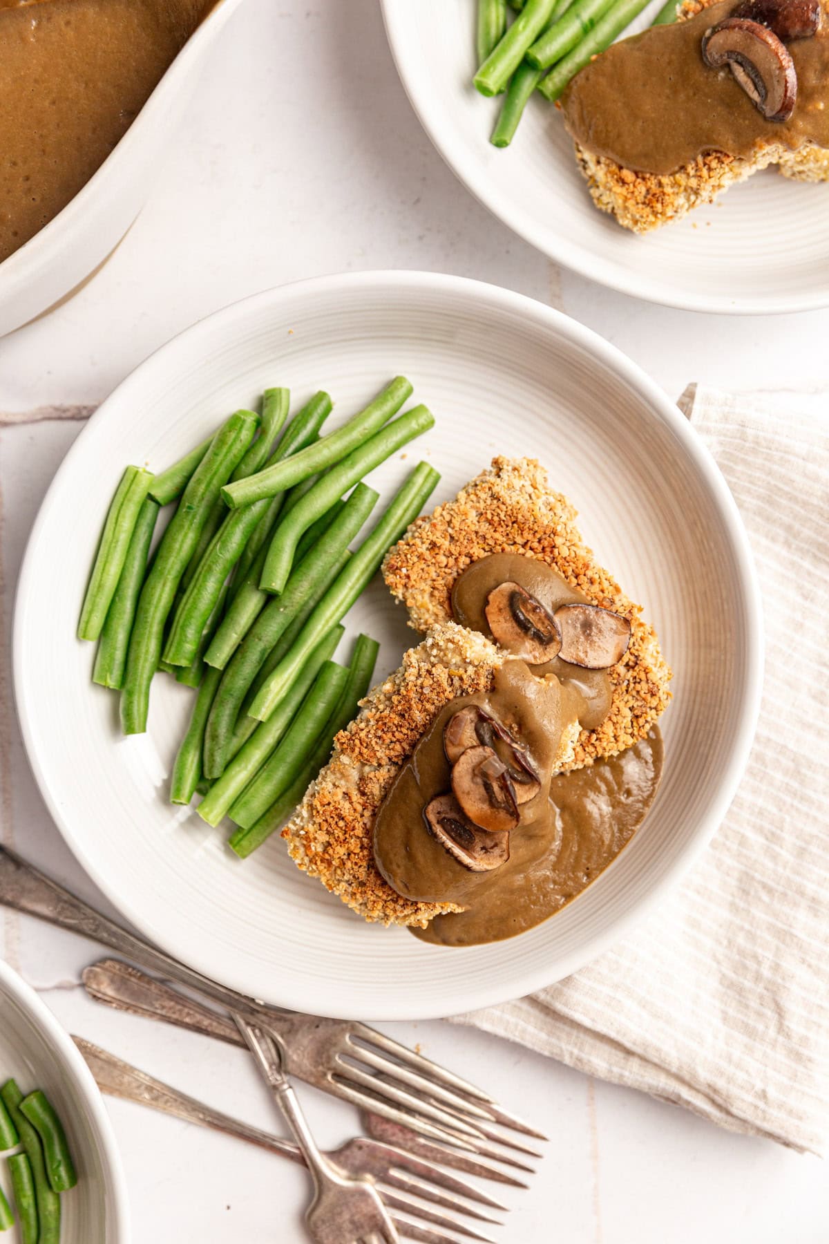 Several plates of tofu and gravy, served with green beans.