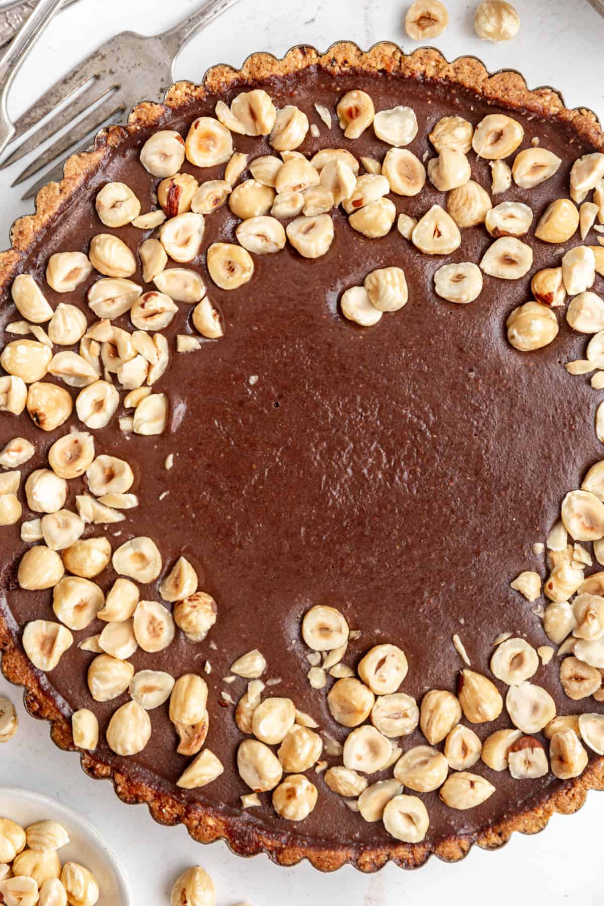 Hazelnut pieces covering a vegan chocolate hazelnut tart.