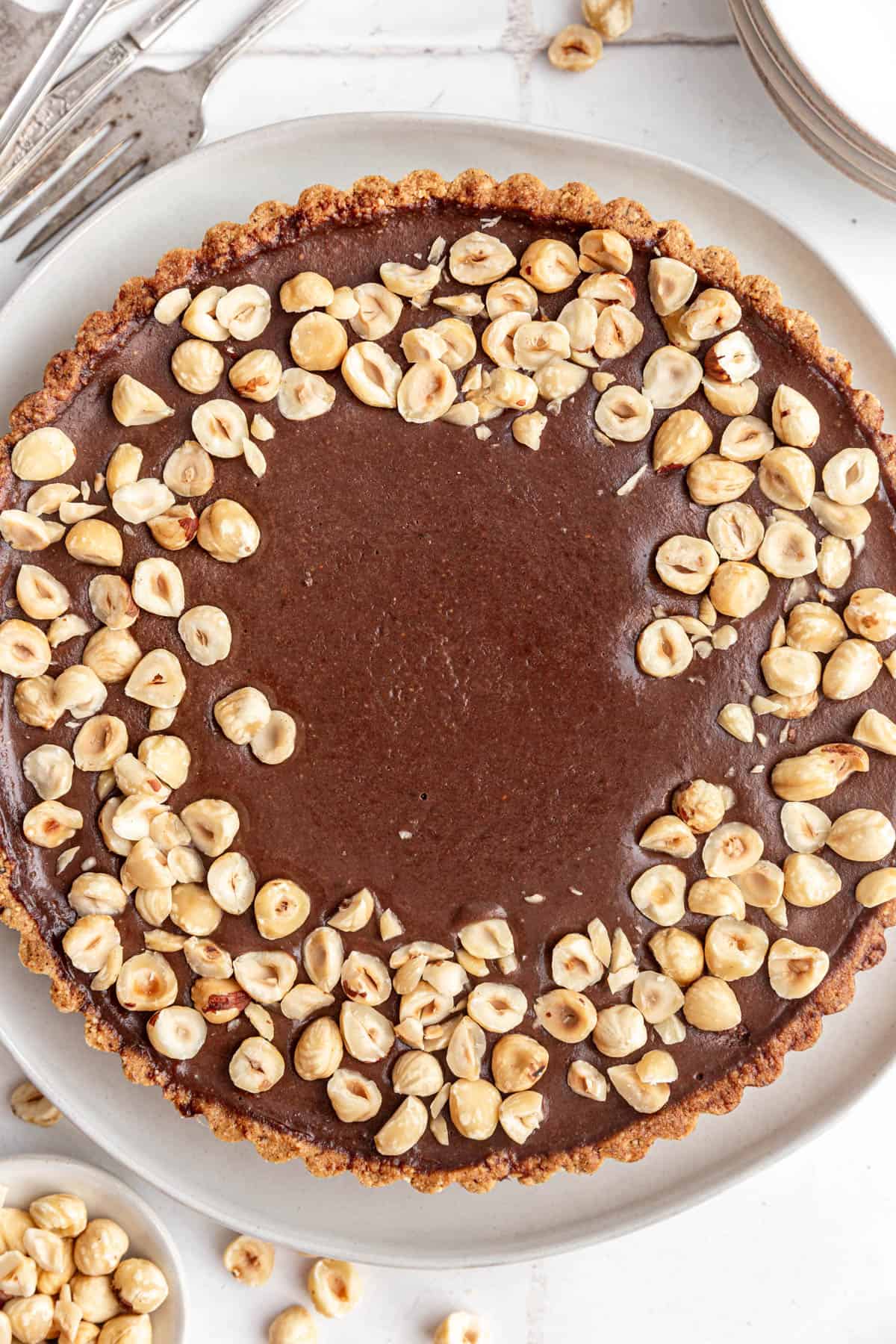 A whole Vegan Chocolate Hazelnut Tart on a plate, ready to serve.