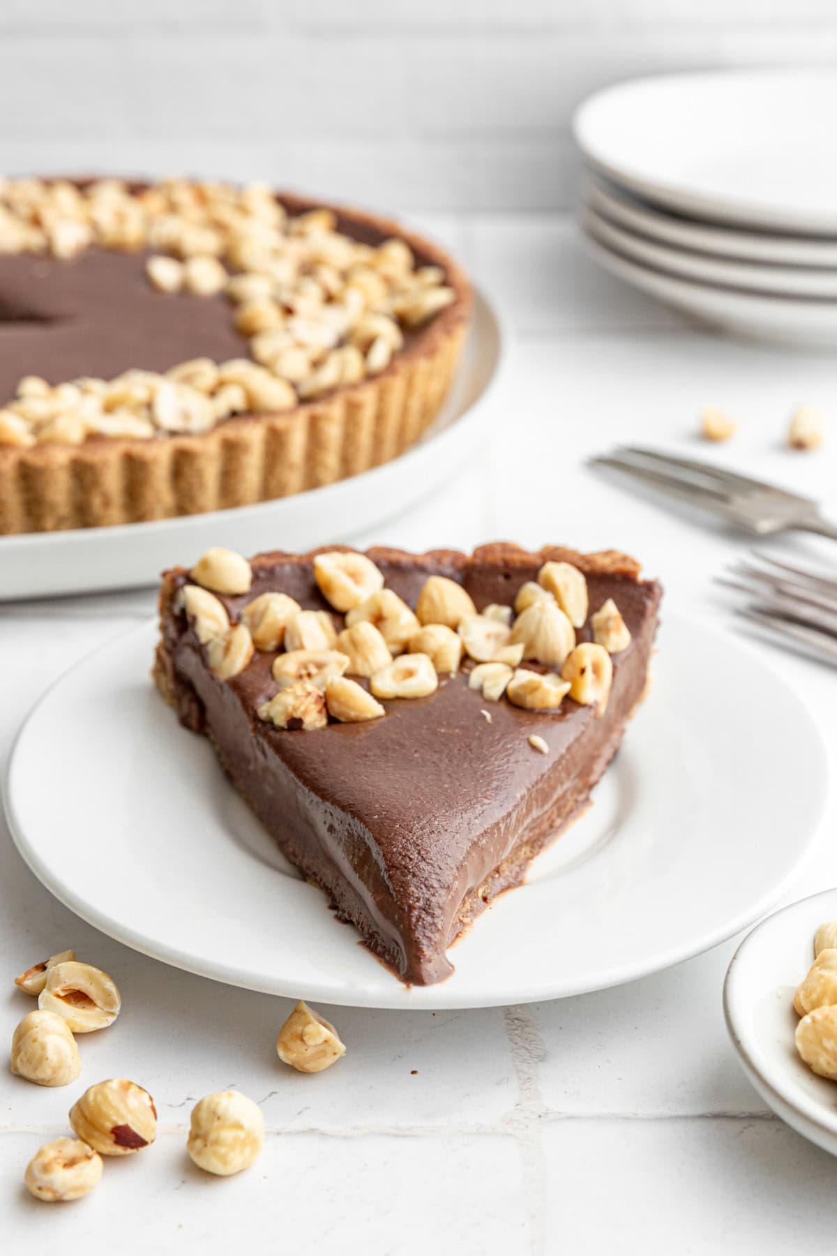 A slice of Vegan Chocolate Hazelnut Tart on a plate, with forks.