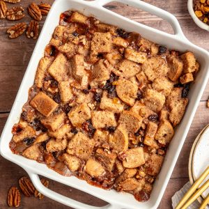 A dish of freshly baked vegan gluten free bread pudding, drizzled with maple syrup.