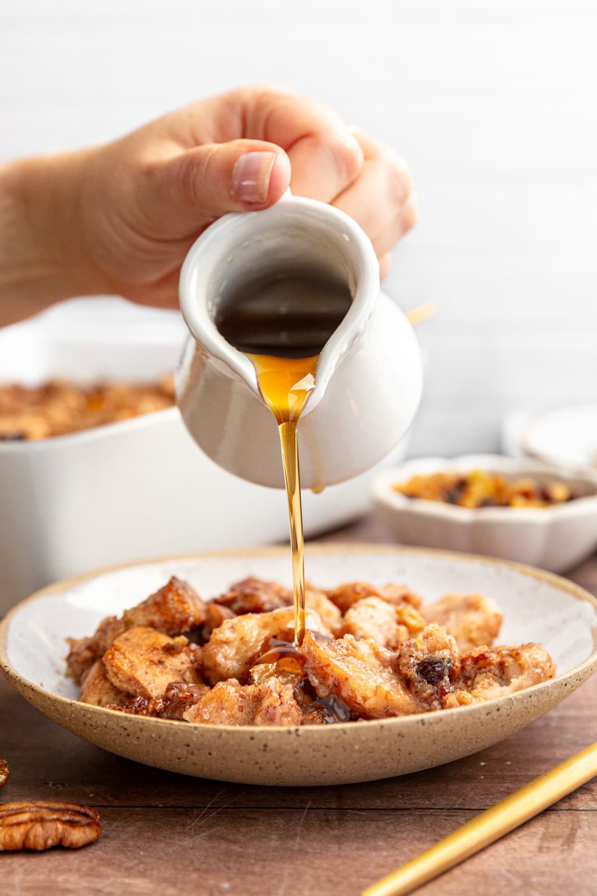 A bowl of bread pudding drizzled with maple syrup.