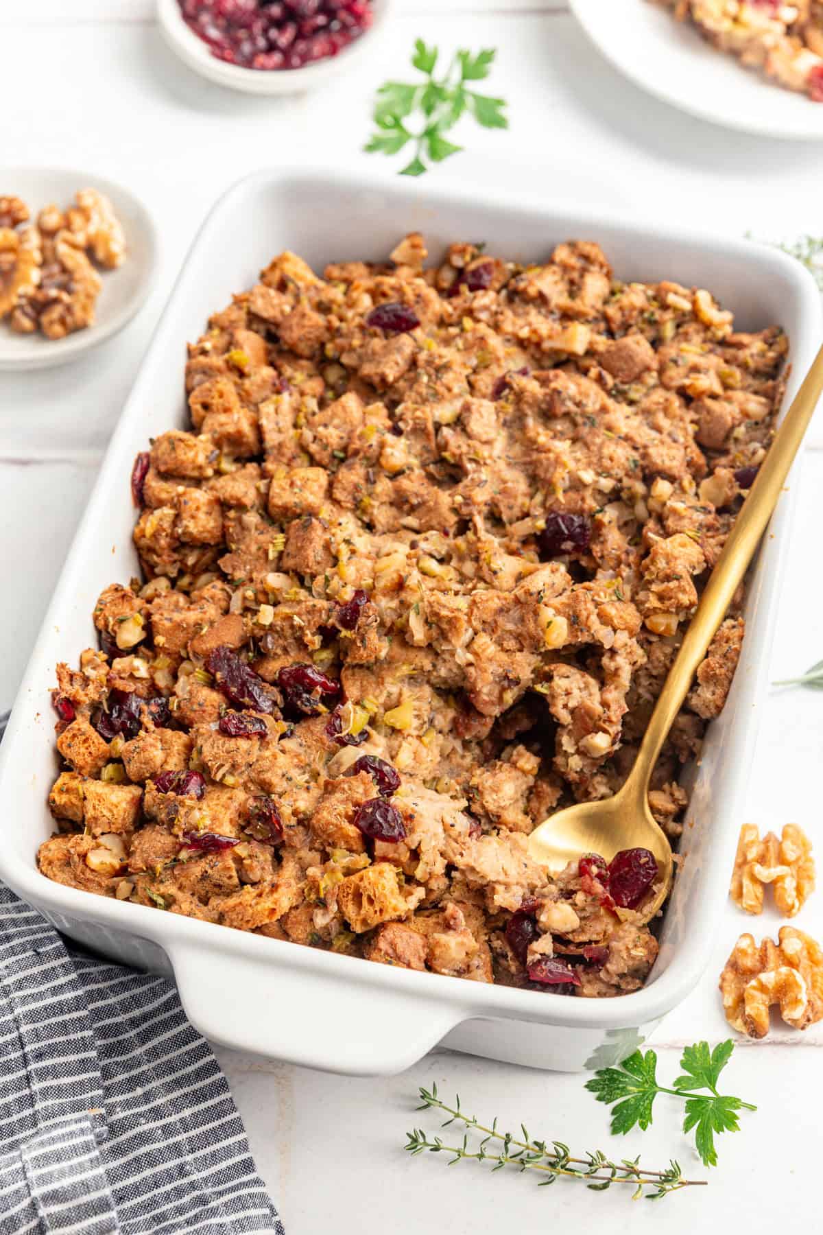 A casserole dish of Vegan Gluten Free Stuffing, with a spoon scooping out a serving.