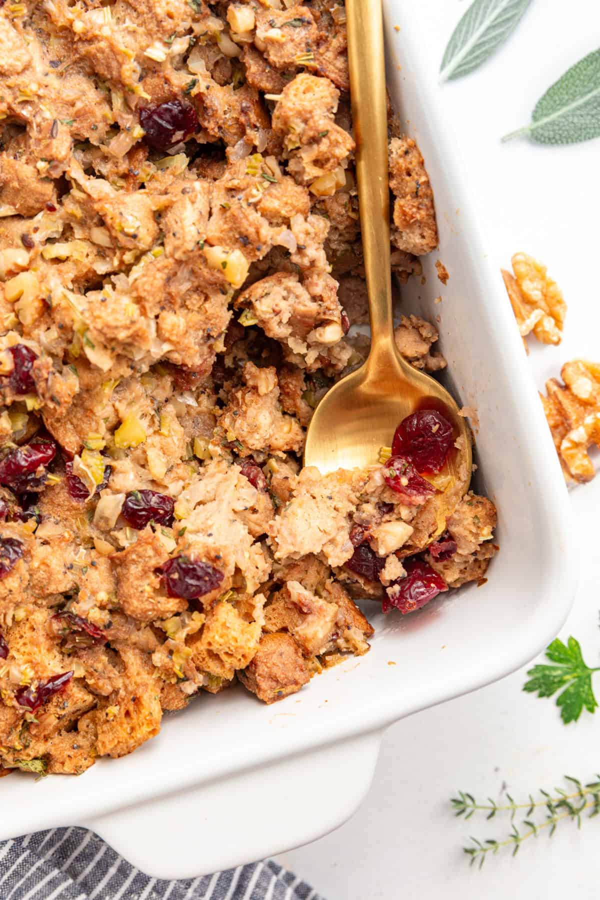 A casserole dish of Vegan Gluten Free Stuffing, with a spoon scooping out a serving.