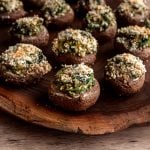 A tofu spinach stuffed mushroom on a wooden board.