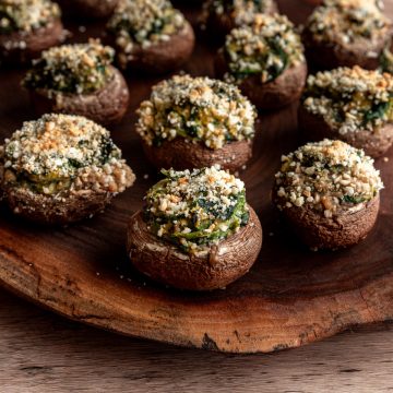 A tofu spinach stuffed mushroom on a wooden board.
