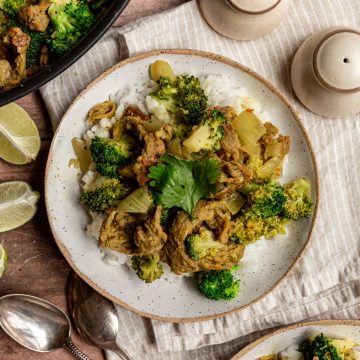 Two bowls of vegan chicken curry next to a pan of curry.