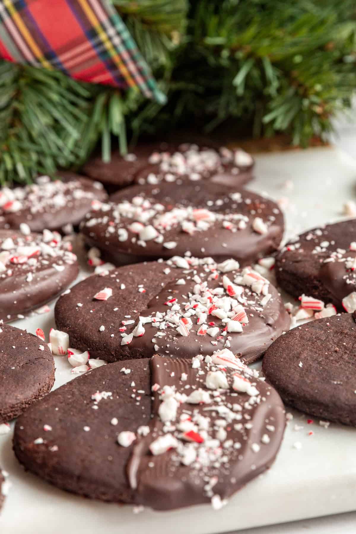 A row of Vegan Chocolate Peppermint Cookies and a Christmas wreath.