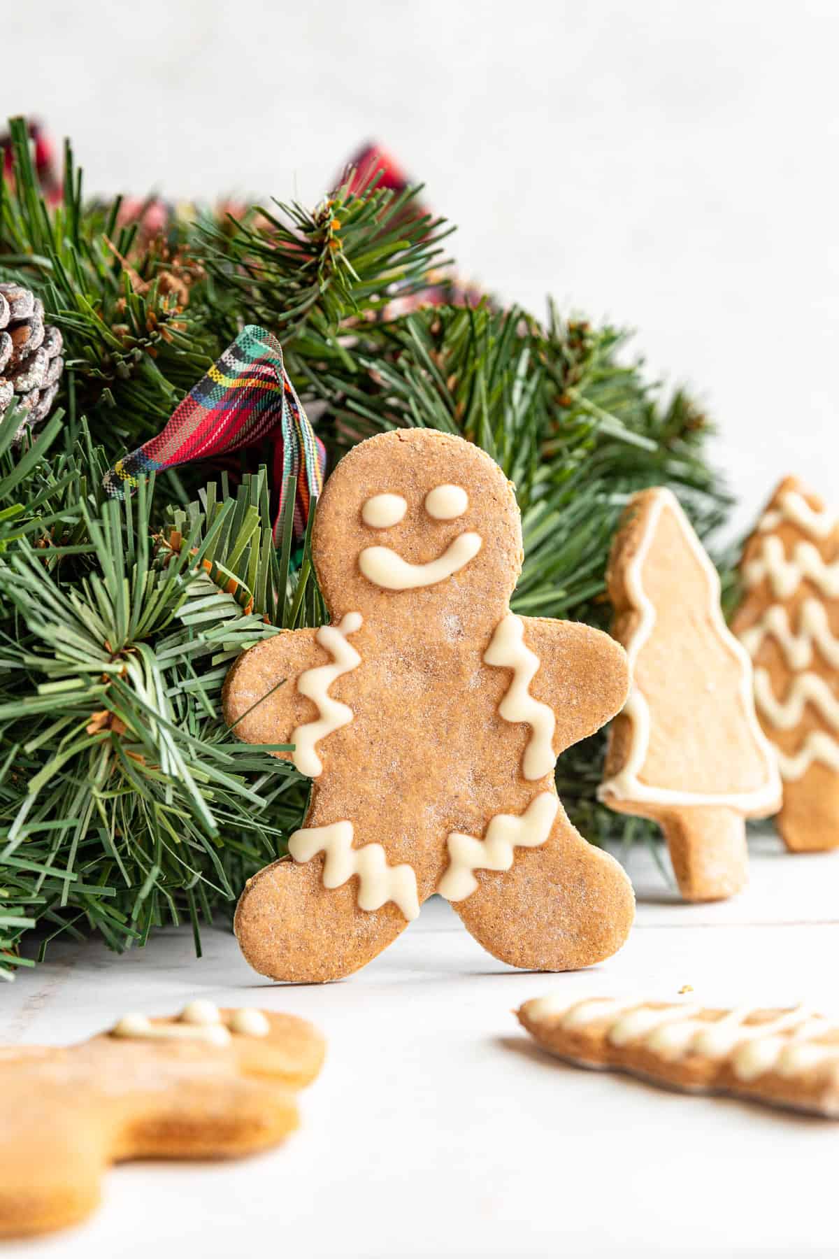 A gingerbread man standing up next to a Christmas wreath.
