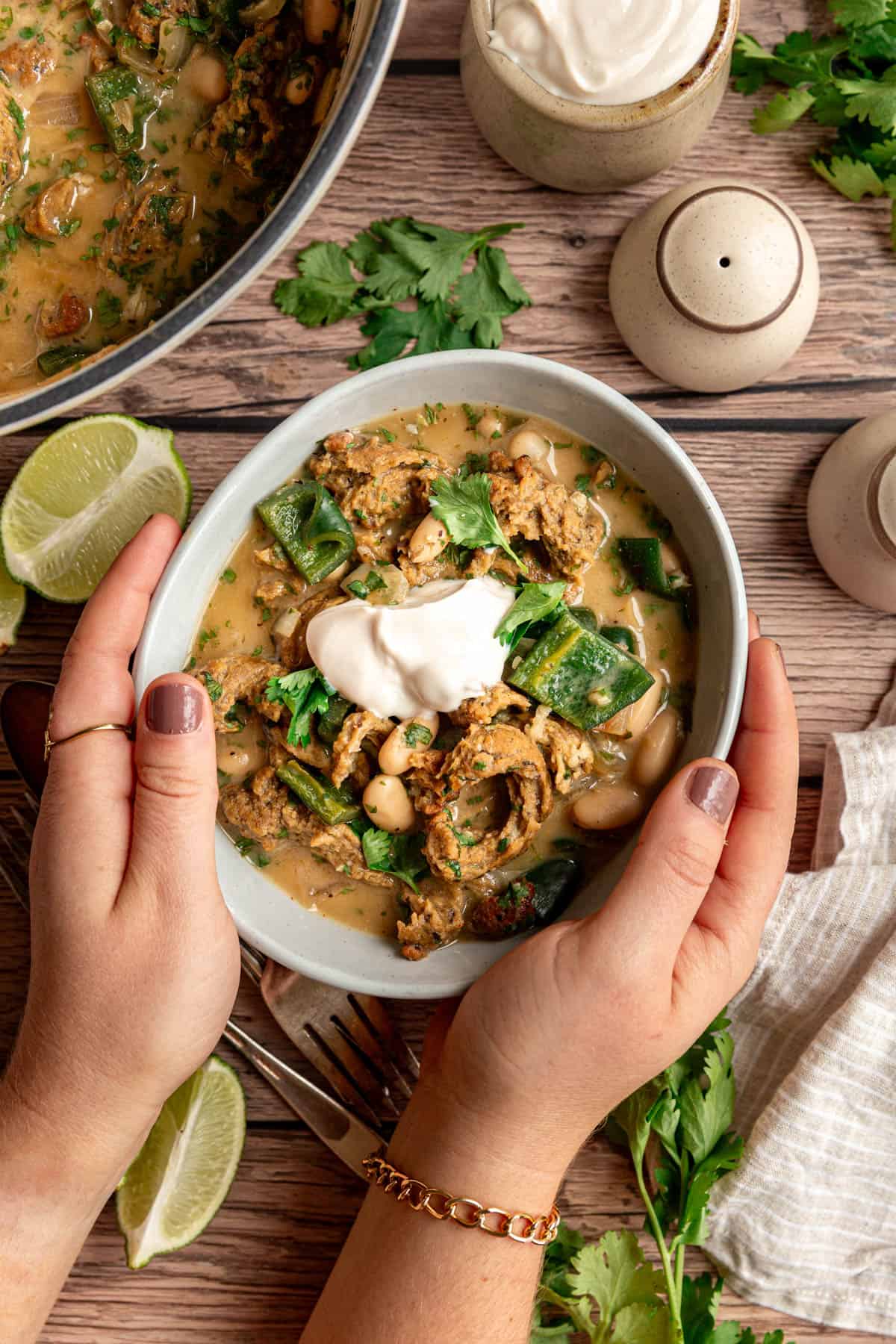 Hands holding a bowl of vegan white chicken chili.