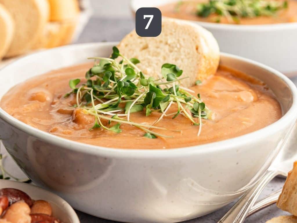 Easy Vegan Pinto Bean Soup served with bread and microgreens.