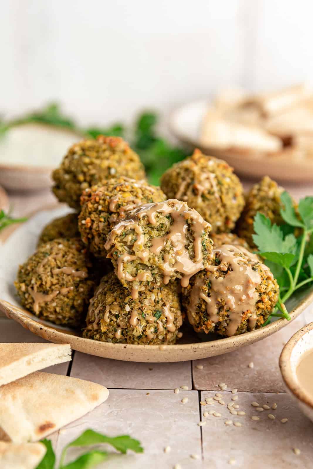 Vegan Oil-Free Falafel with a bite taken out and a drizzle of tahini.