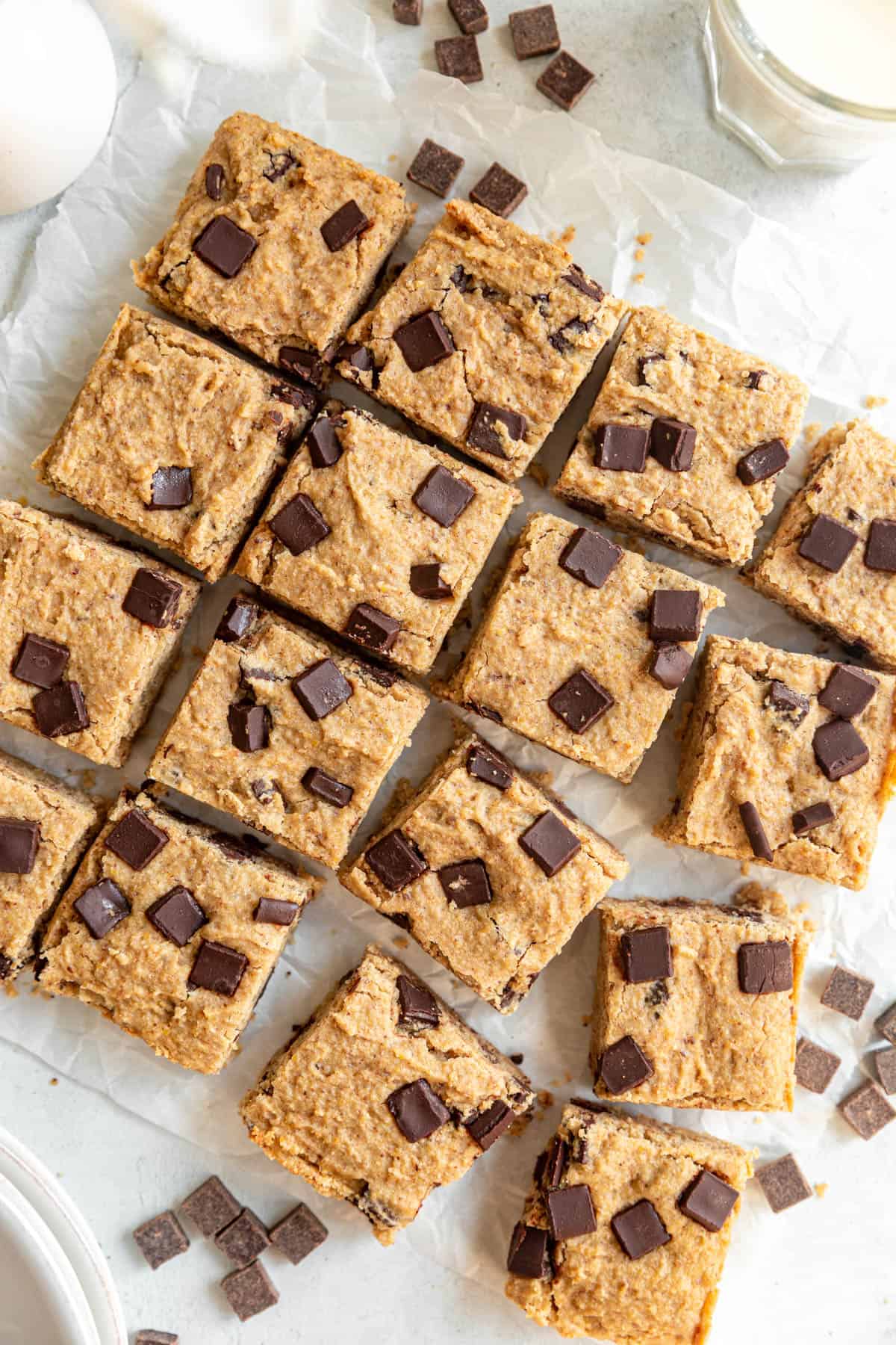 A tray of Healthy Vegan Chocolate Chip Chickpea Blondies sliced and served with milk.