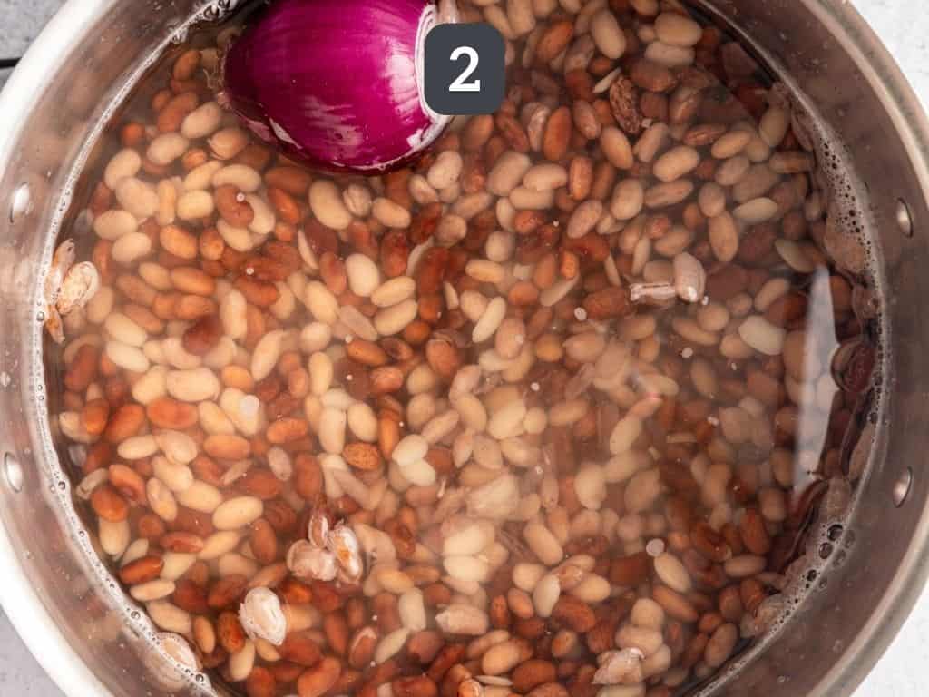 Pinto beans in a pot cooking with onion.