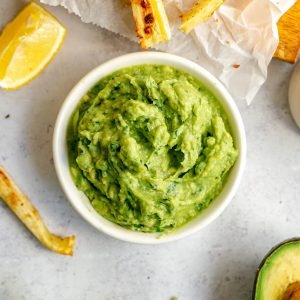 A bowl of avocado dip, served with parsnip fries.