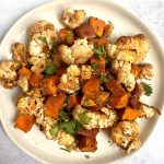 A plate of balsamic roasted cauliflower and sweet potatoes garnished with parsley.