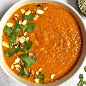 A bowl of Caramelized Carrot Soup garnished with cilantro and almonds.