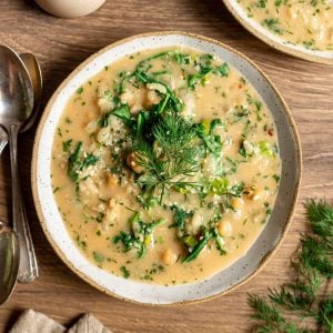 A bowl of chickpea yogurt soup garnished with dill.