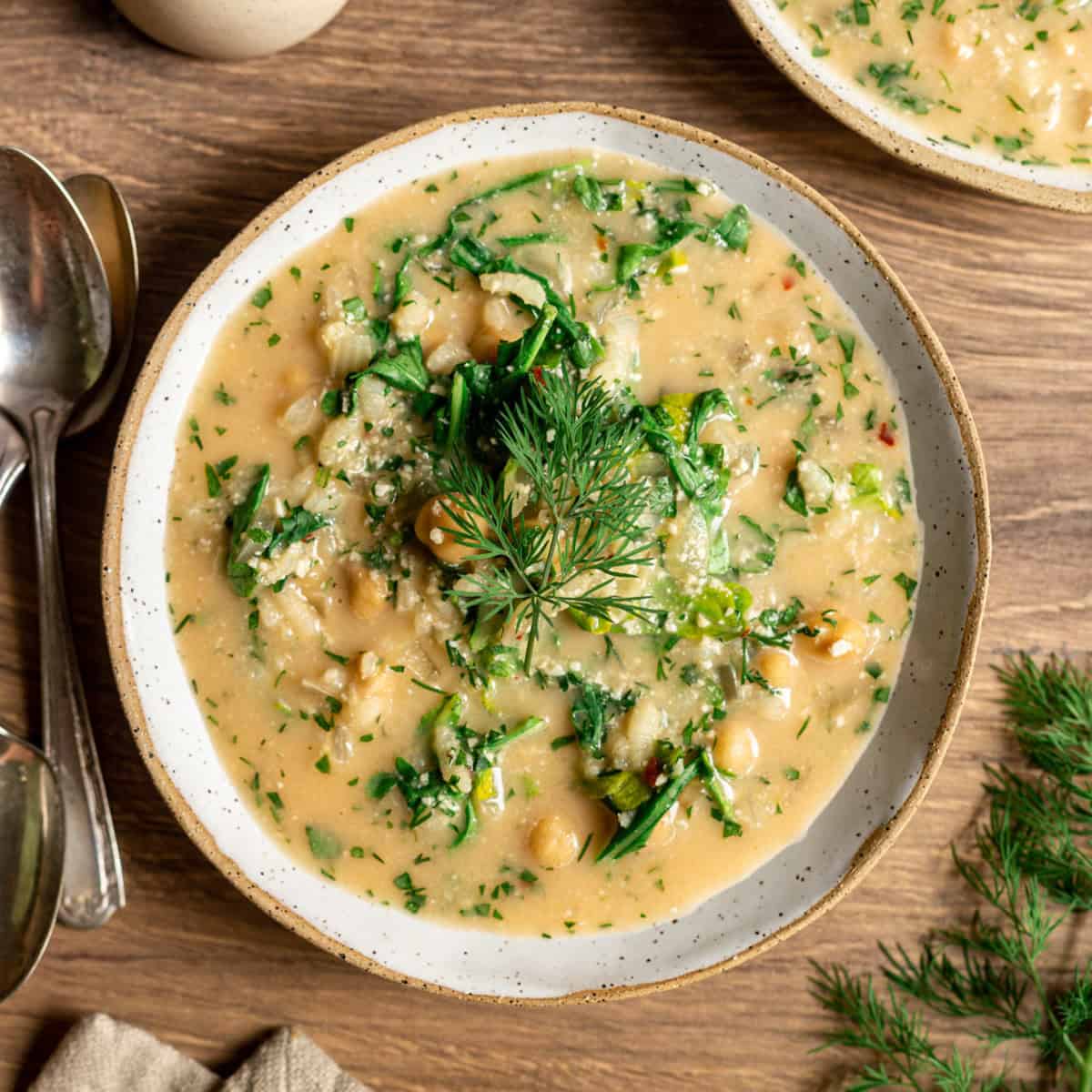 A bowl of chickpea yogurt soup garnished with dill.