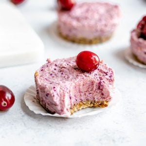 A cranberry cheesecake cup with a bite taken out.