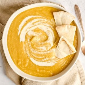 A bowl of curried parsnip soup topped with pitas.