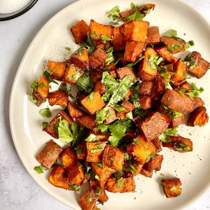 A plate of date glazed spicy sweet potatoes garnished with cilantro.