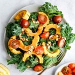 A plate of delicata squash kale salad, with a fork, ready to serve.