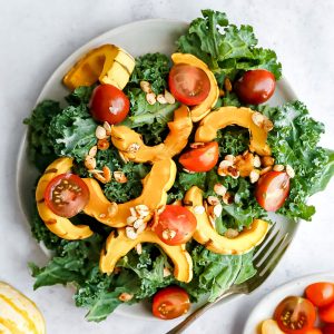 A plate of delicata squash kale salad, with a fork, ready to serve.