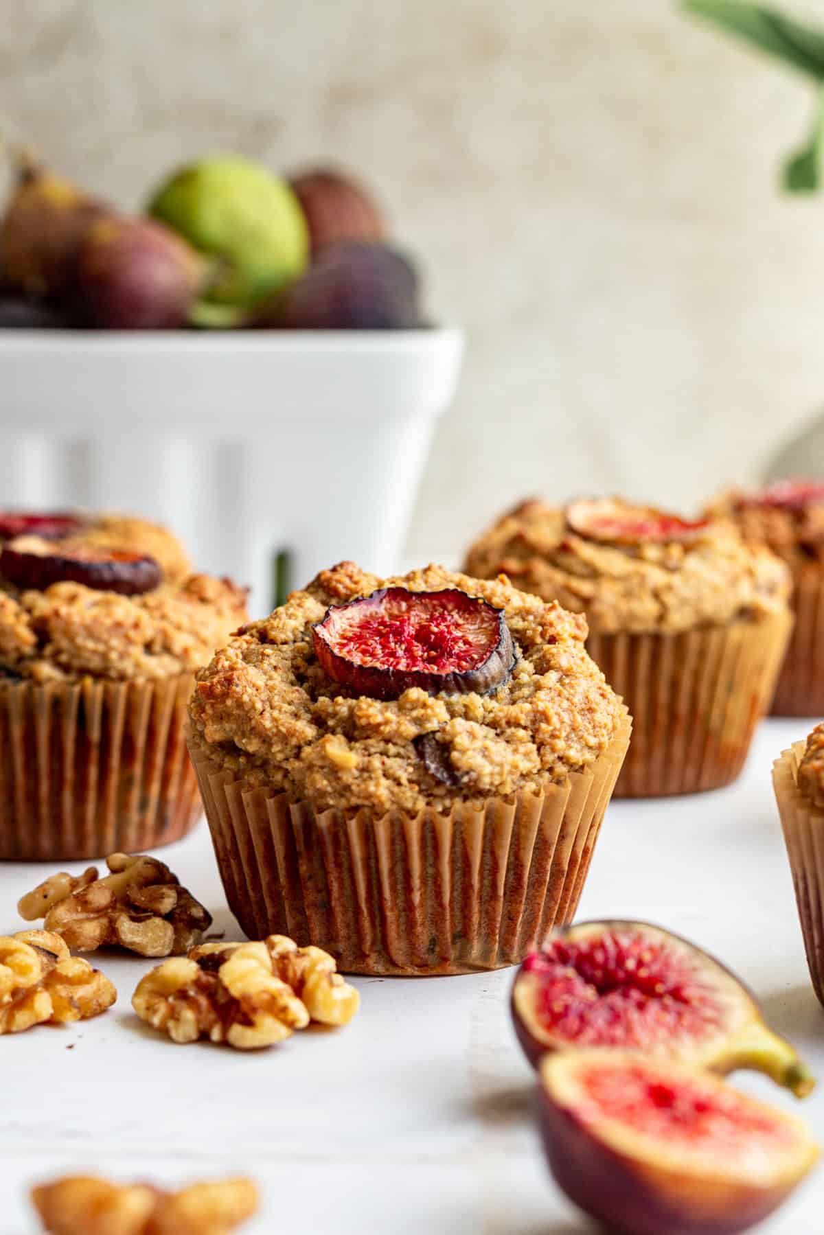 A fresh fig muffin on a countertop with walnuts and figs.