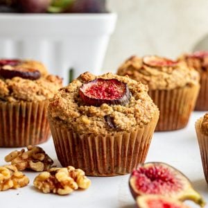 A fresh fig muffin on a countertop with walnuts and figs.