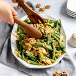 A person scooping a platter of oil-free green beans.