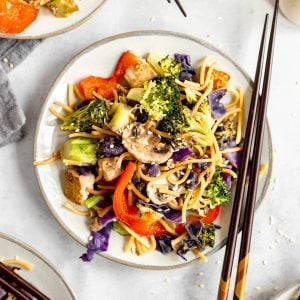 A plate of plant-based lo mein served with chopsticks.