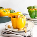 A yellow stuffed pepper on a plate with a fork, ready to serve.