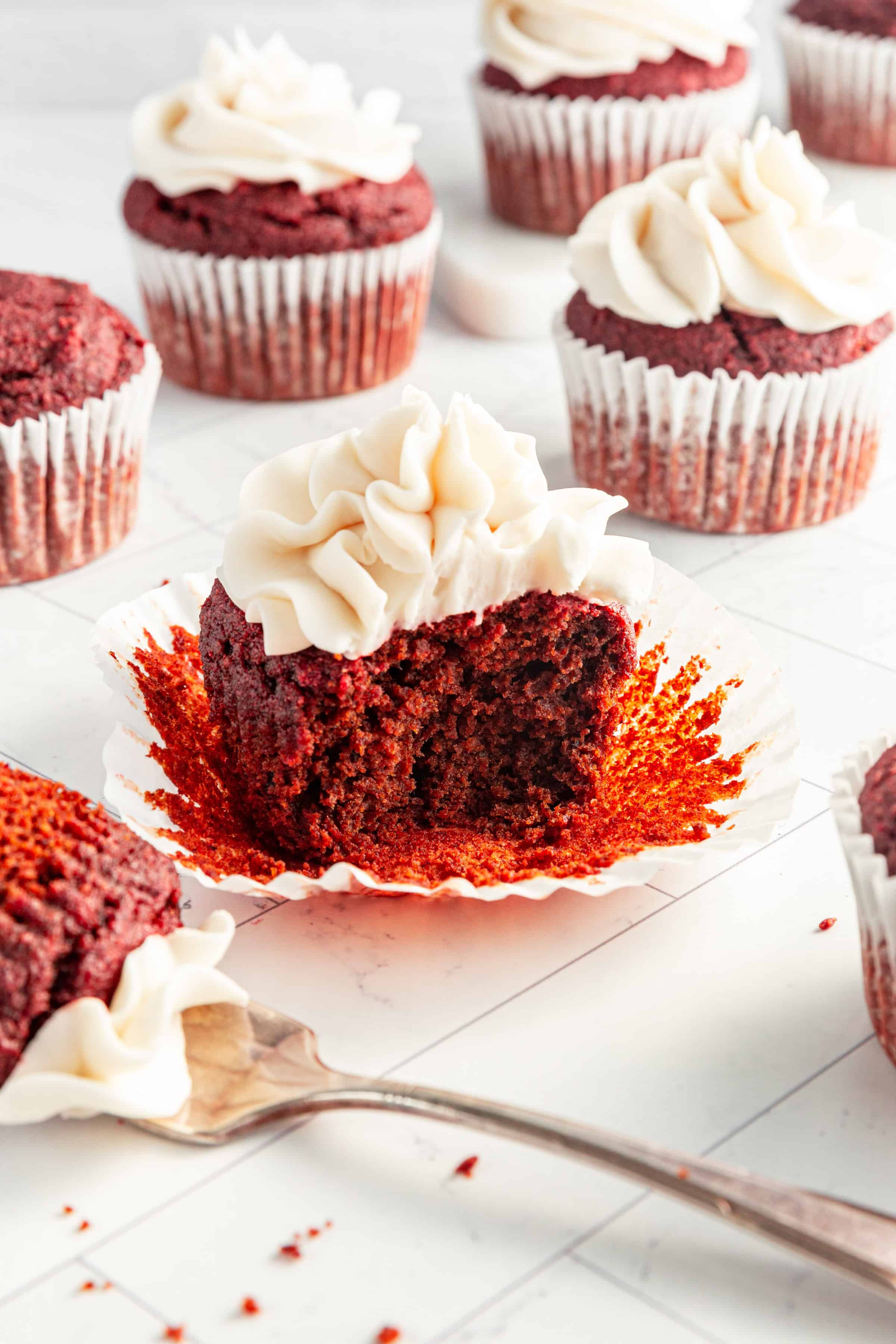 A red velvet cupcake with a forkful taken out.