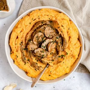 A bowl of sweet potato mashed potatoes topped with mushroom gravy.