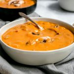 A bowl of sweet potato miso mushroom soup, with a spoon, ready to serve.