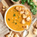 A bowl of vegan garlic chickpea soup, garnished with homemade croutons.